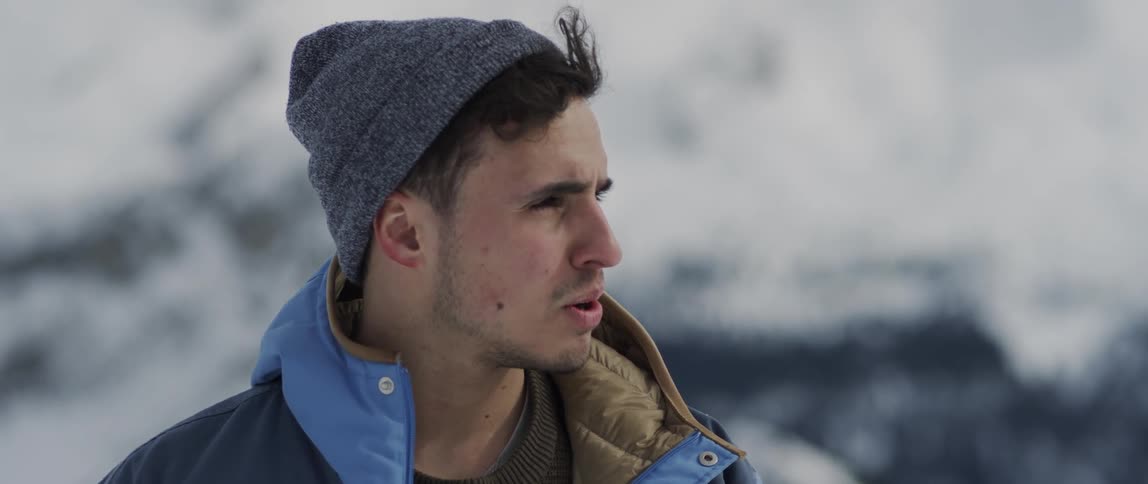 A man wears a coat in snowy mountains