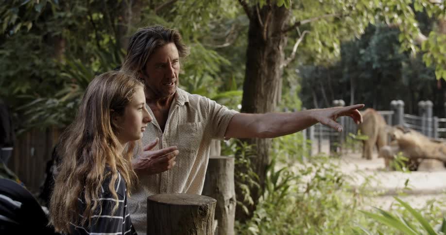 A man and teenage girl look at animals in a zoo