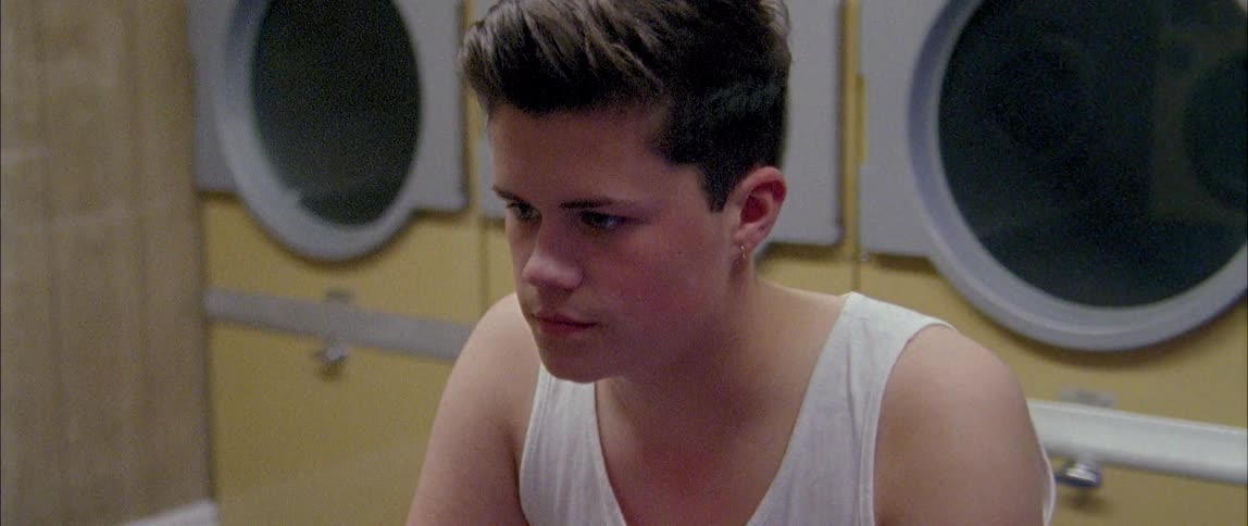 A teenager sits in a laundromat