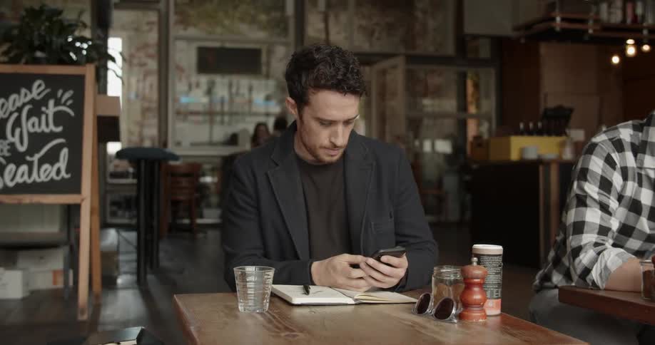 A man looks up from his phone in the restaurant