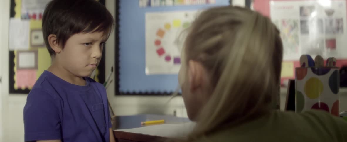Forlorn looking child being talked to by teacher