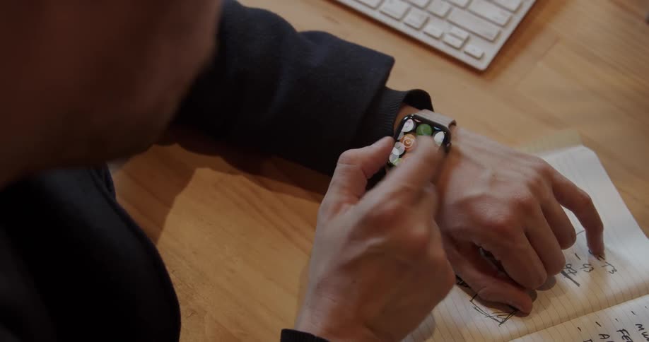 A man uses a smart watch at a desk