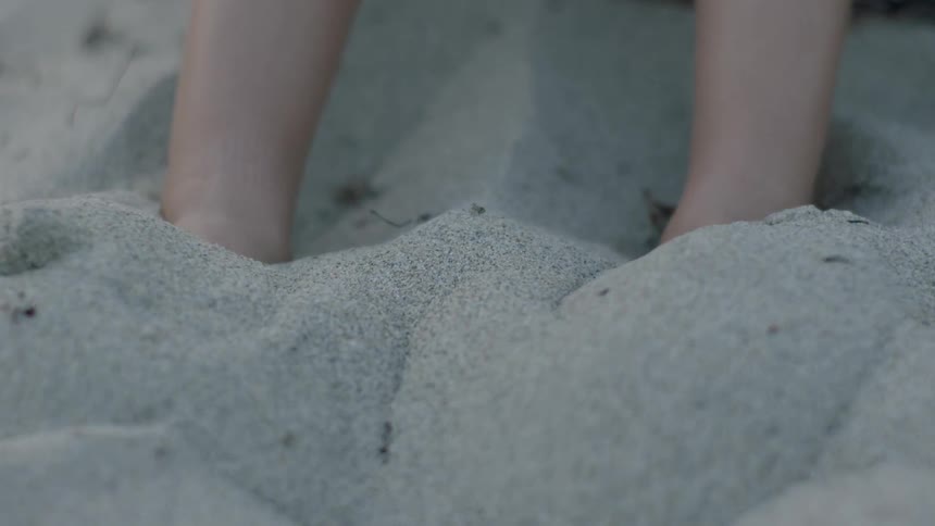 A person kicks their feet in the sand