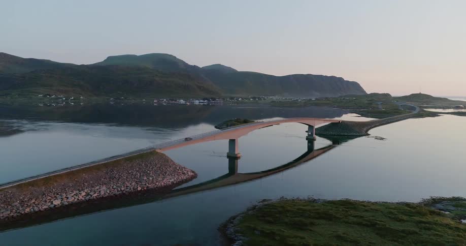 A car drives over a bridge at sunset