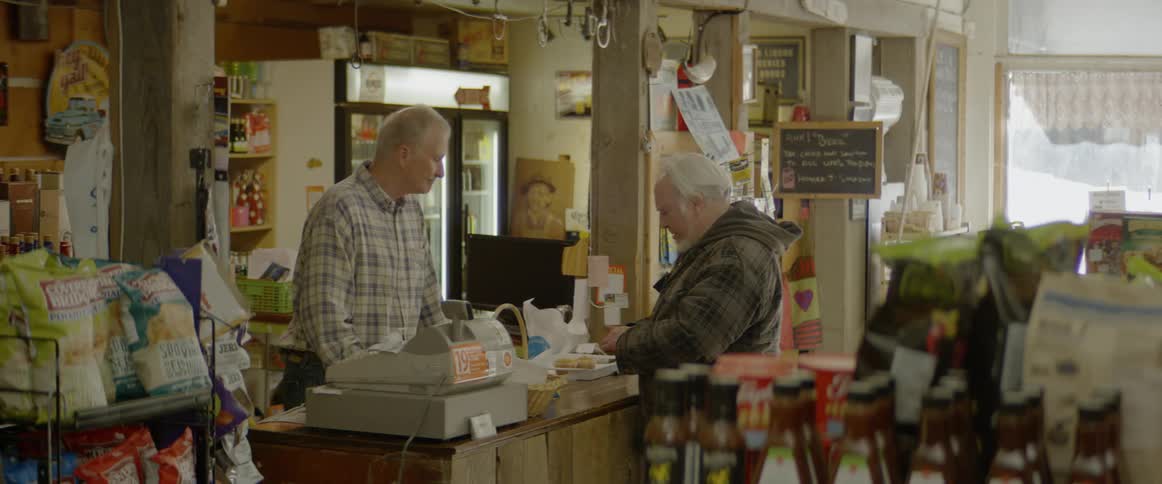 A man talks with a cashier in a convenience store