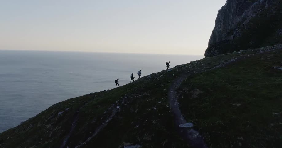 Hikers walk up a coastal mountainside