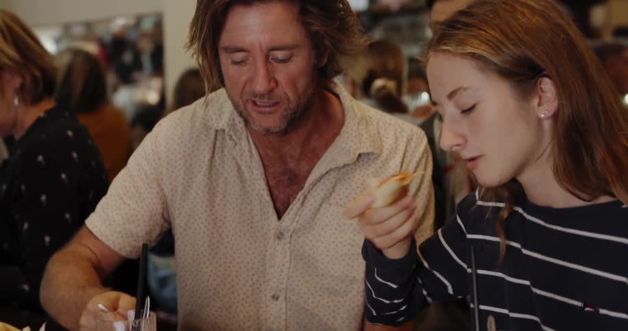 Two people eat and talk at a restaurant