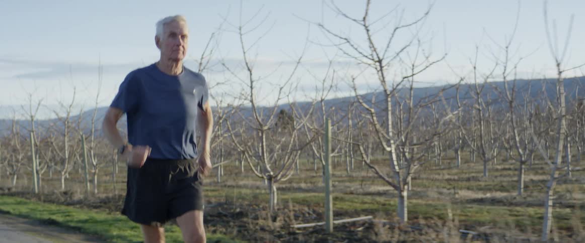 A man jogging along a tree farm on a cloudy day