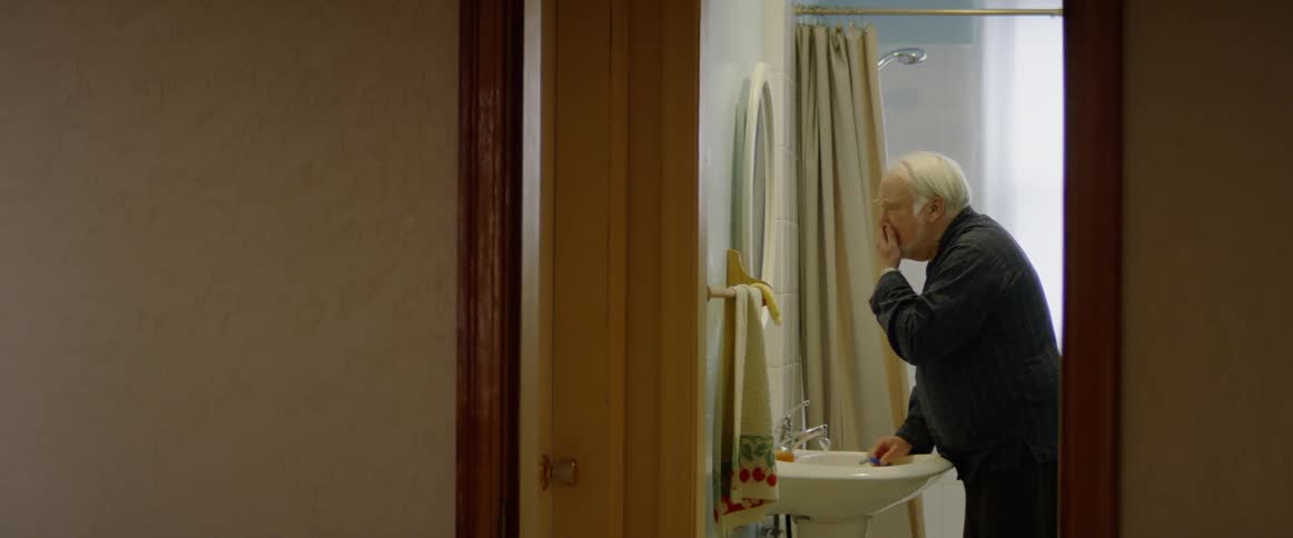 A man applies soap to his face and begins to shave
