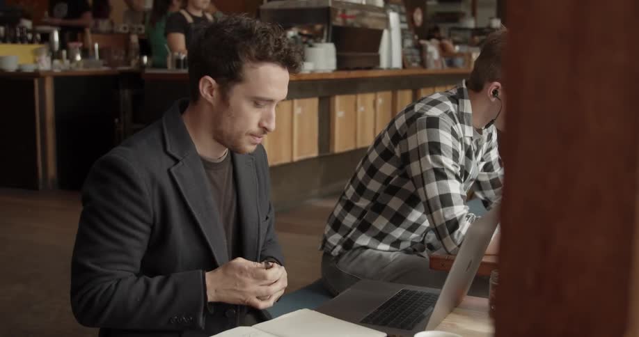 A man writes in a notebook in a coffee shop