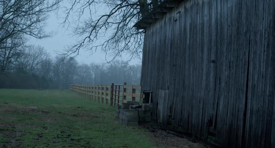 Cinder blocks are stacked outside of a wood barn