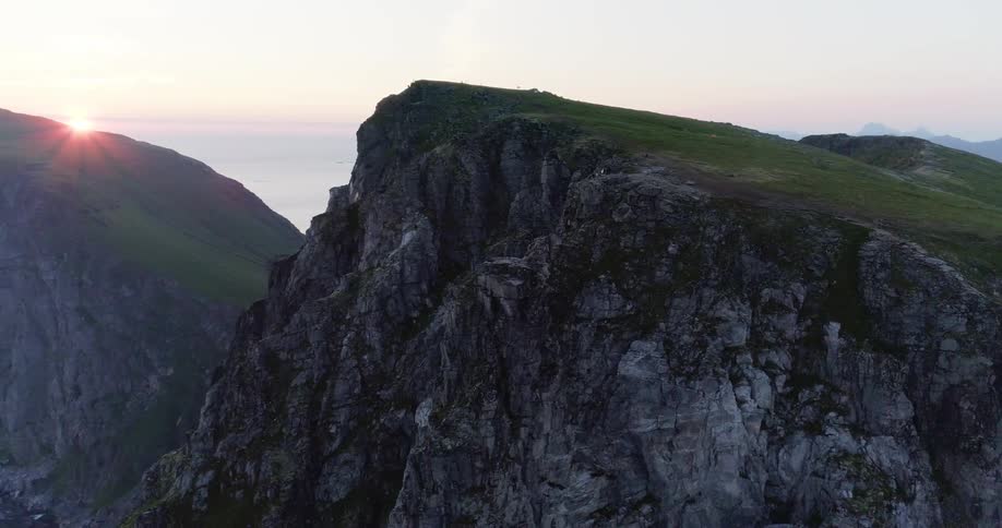 The tall cliff is covered with green at sunset