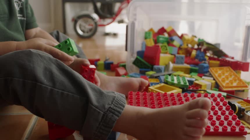 A young boy plays with blocks on the floor