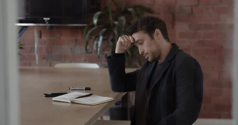 Man puts down his cellphone and then shakes his head
