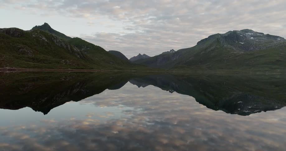 Mountains and clouds are reflected in a calm lake
