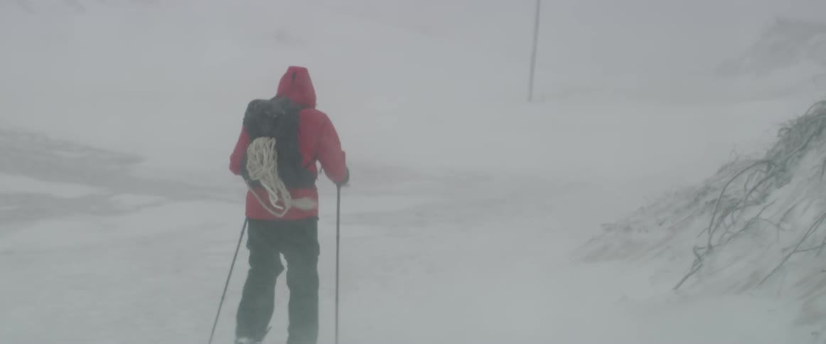 The man hikes with snow shoes as the snow falls fast