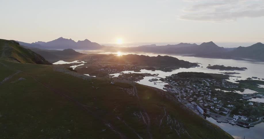 The sun sets on the horizon over peaks and water