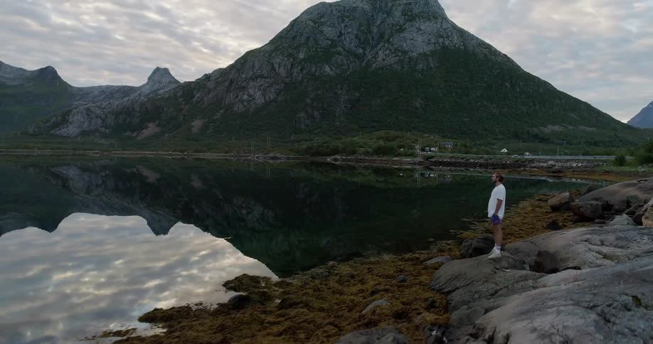 A man stands on the rocks looking over the calm lake