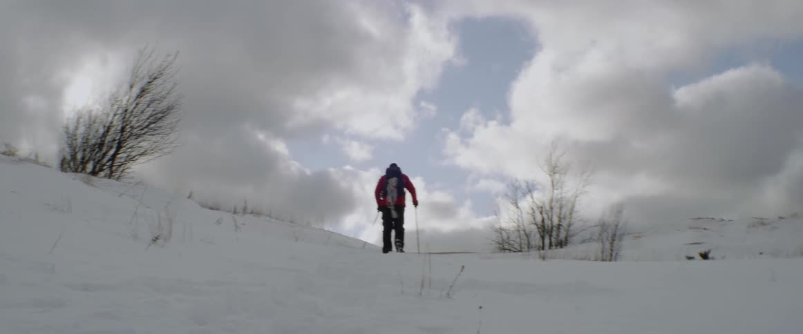 A man climbs up a snowy hill