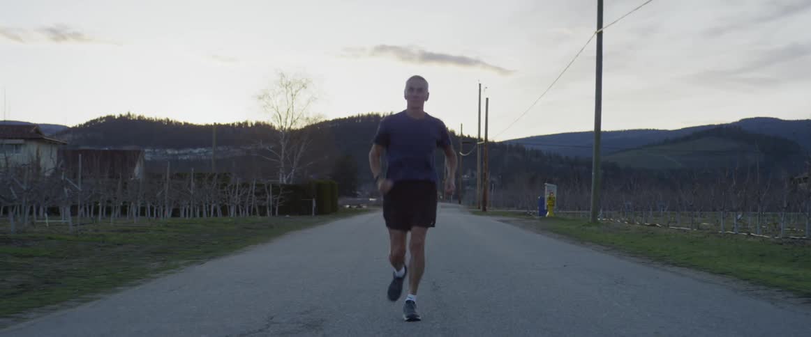 A man jogs on a rural road at sunset
