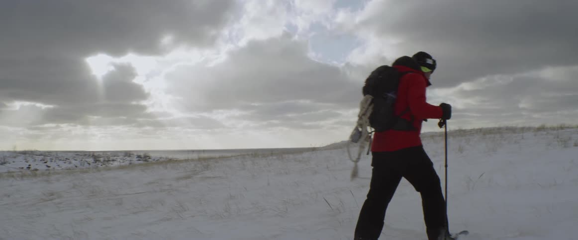 A man stands atop a snowy hill and begins to climb it