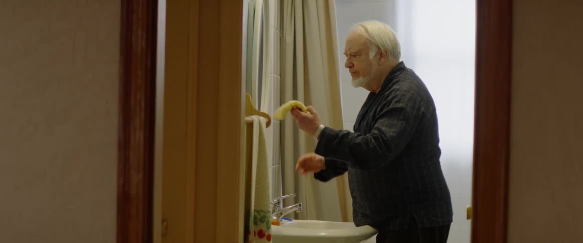 A man wipes his face in front of the mirror