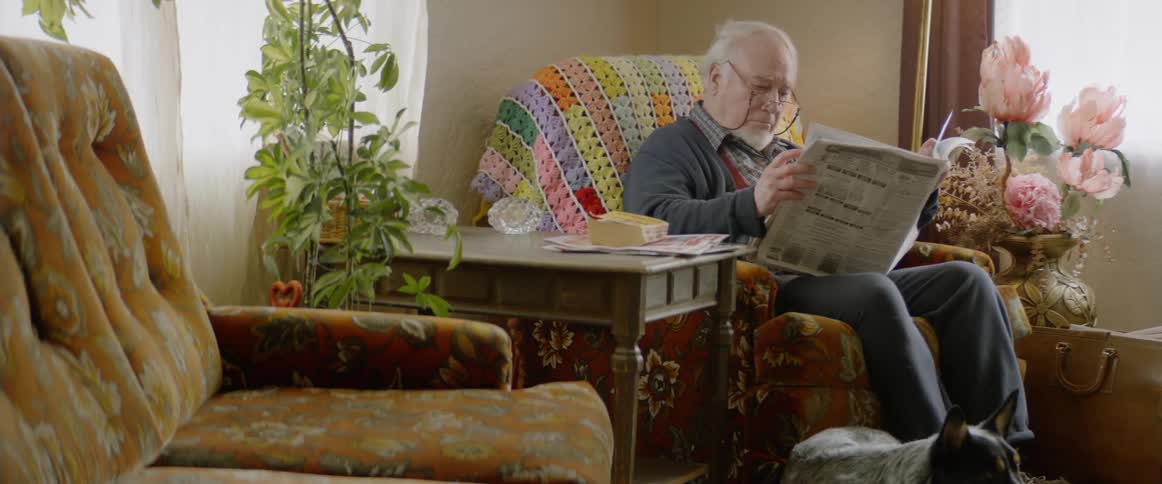 Elderly man reads a newspaper at home