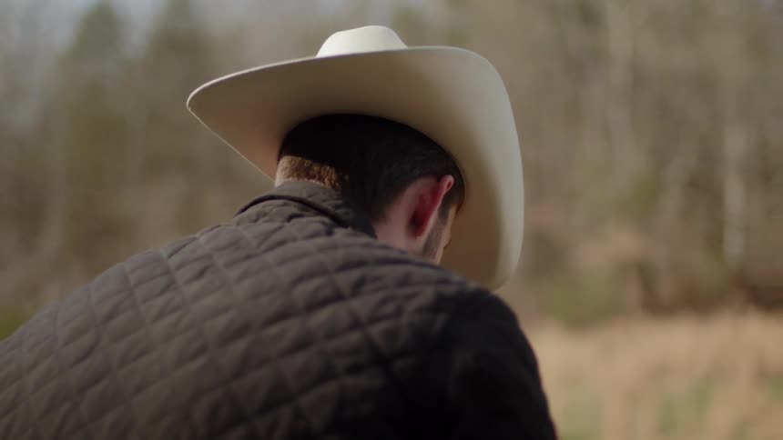 A cowboy sits outside on a cloudy day