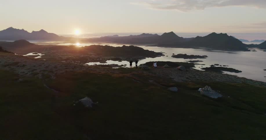 People are standing together on the cliff by the shore