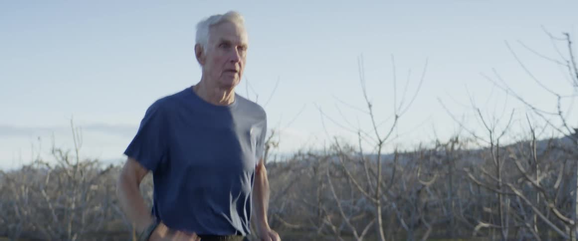 A man runs past the trees on a sunny day
