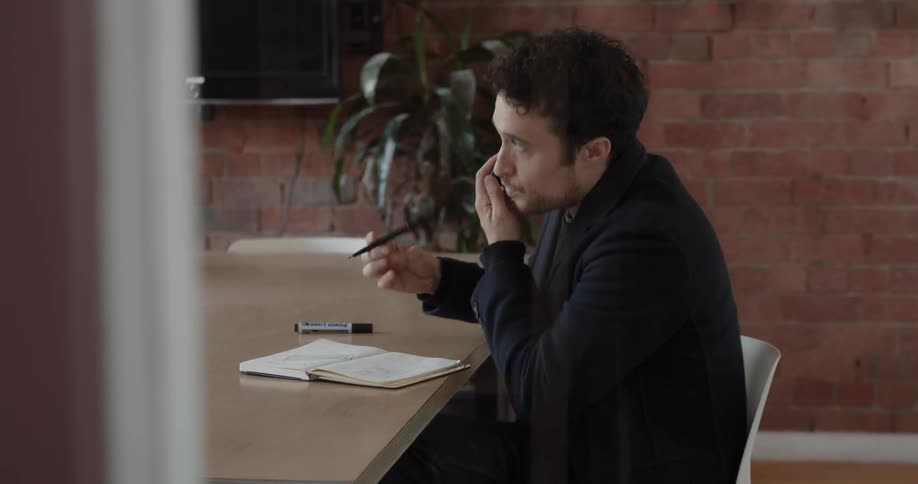 Man talks on a phone in a conference room