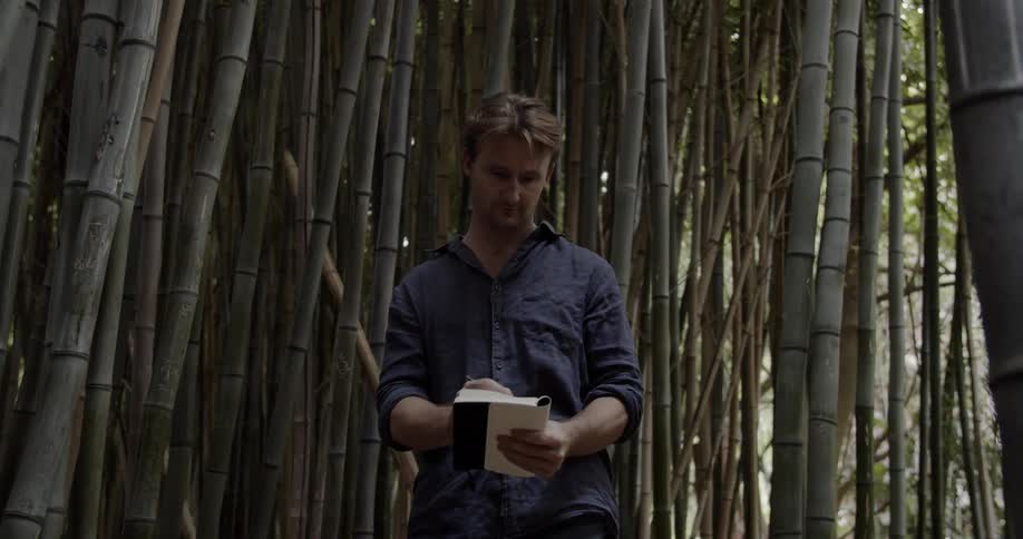 A man writes in a notebook in the woods