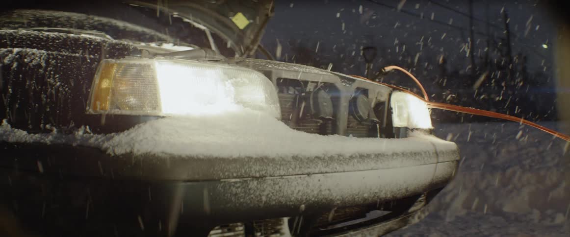 Snow falls on a broken down car