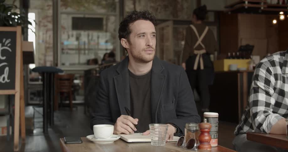 A man is writing in his notebook at a table in the restaurant