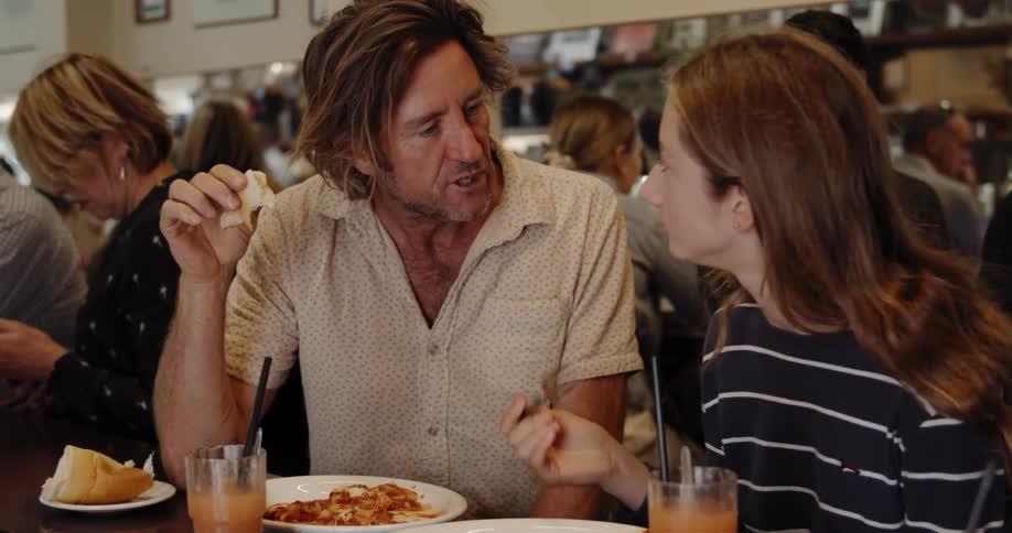 A man and girl talk and eat at the table