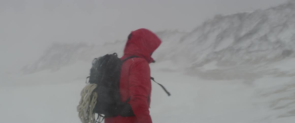 A man looks back as he snowshoes in a snowstorm