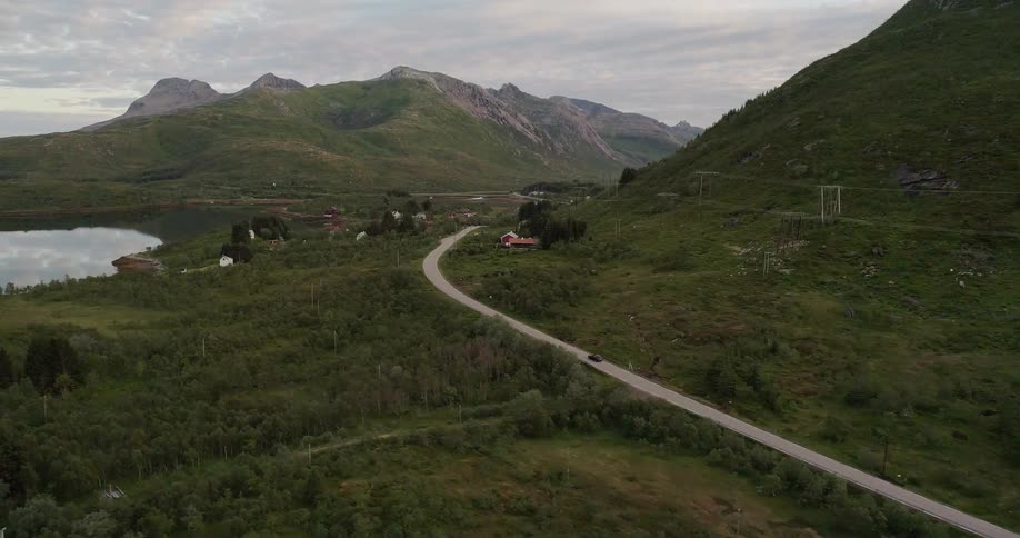 Car drives on a small road winding around a mountain