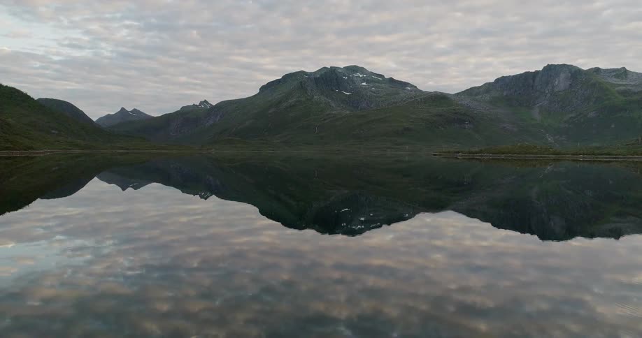The clouds in the sky are reflecting in a lake in a natural landscape at dawn