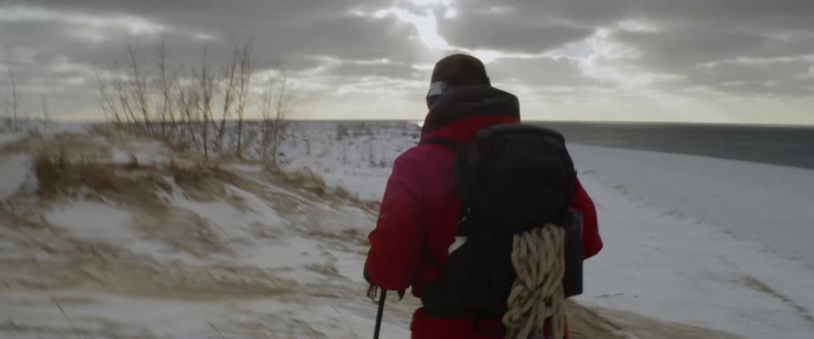 A man hikes up the hills covered in snow