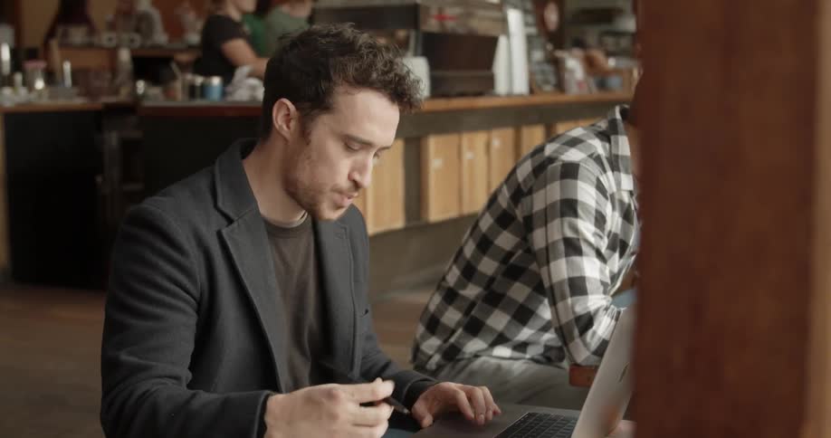 A man writes and types on his laptop in the restaurant