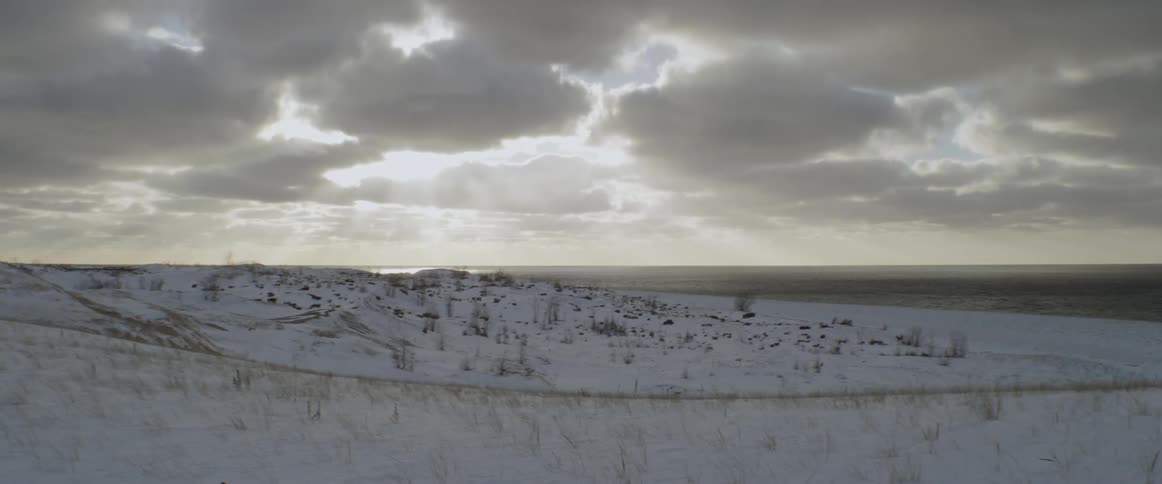 The field near the shore is covered with snow