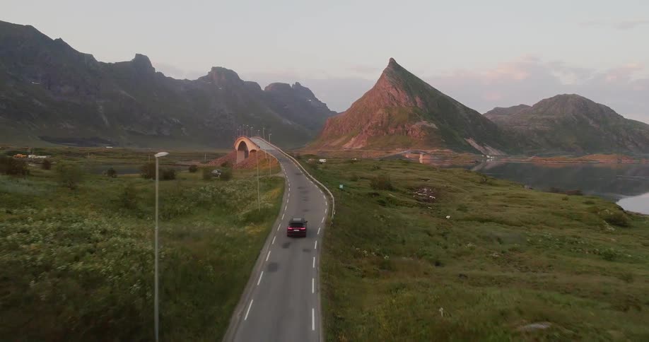 A car drives on a rural road at sunset