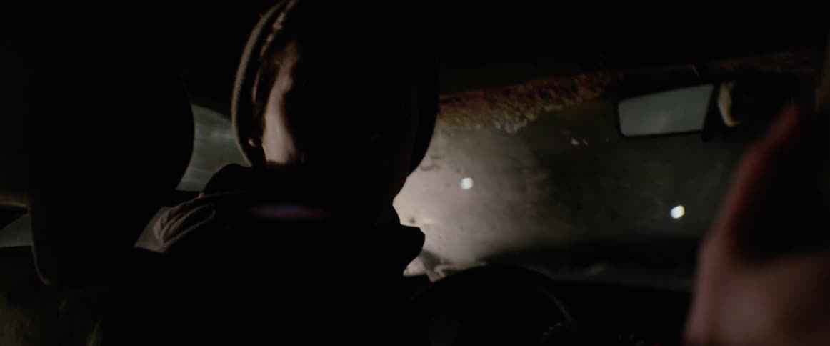 A teenage male is driving a car backwards in a circle at night