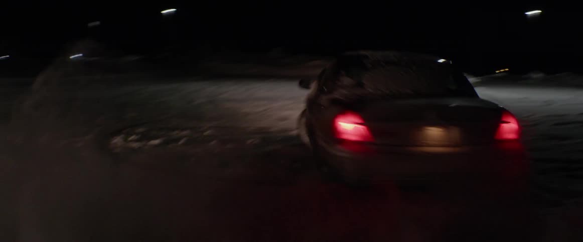A vehicle is doing spin outs in a vacant lot at night in winter