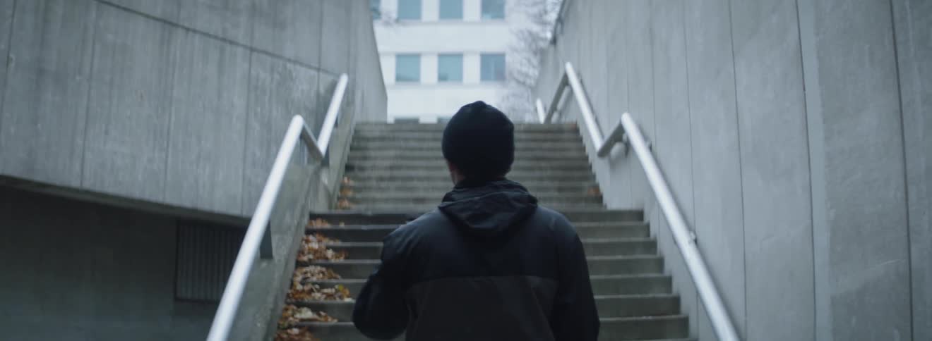 A man is standing at the bottom of stairs outside in daylight taking a photo