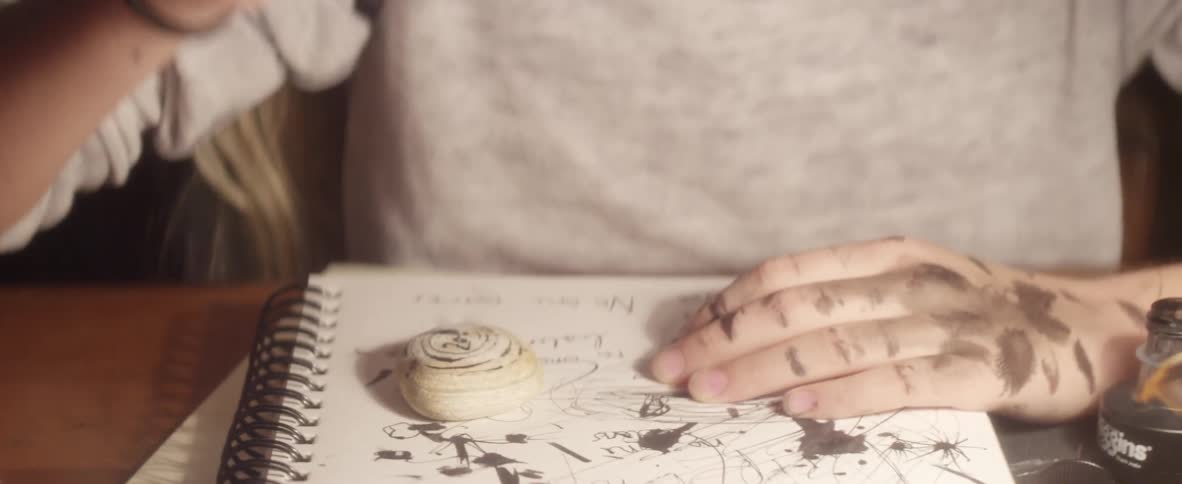 Child brushing her hair away from her face and drawing in a notebook