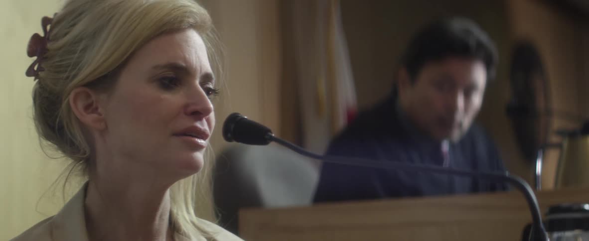 Woman crying on the bench as a judge talks to her