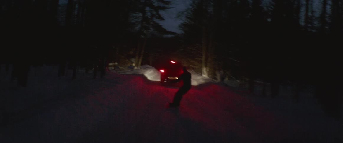 A person is being pulled by a truck as he rides a snowboard