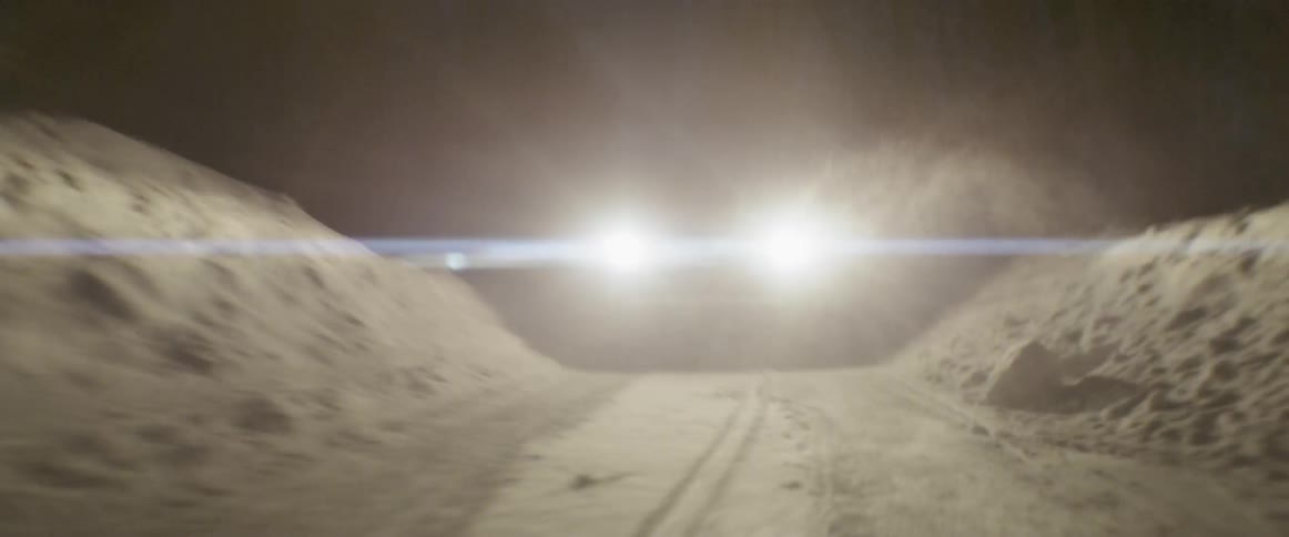 A truck drives on a snowy road at night