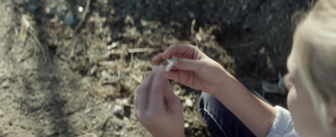 Person picks up a piece of glass from the dirt